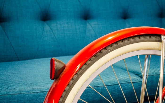 Red bicycle fender and wheel on blue couch