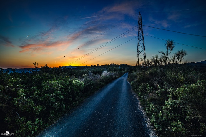 Sunset over a country road with power lines