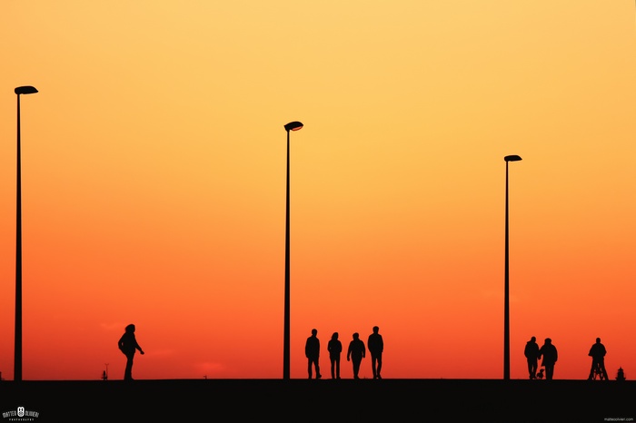 Silhouettes of people and street lights at dusk