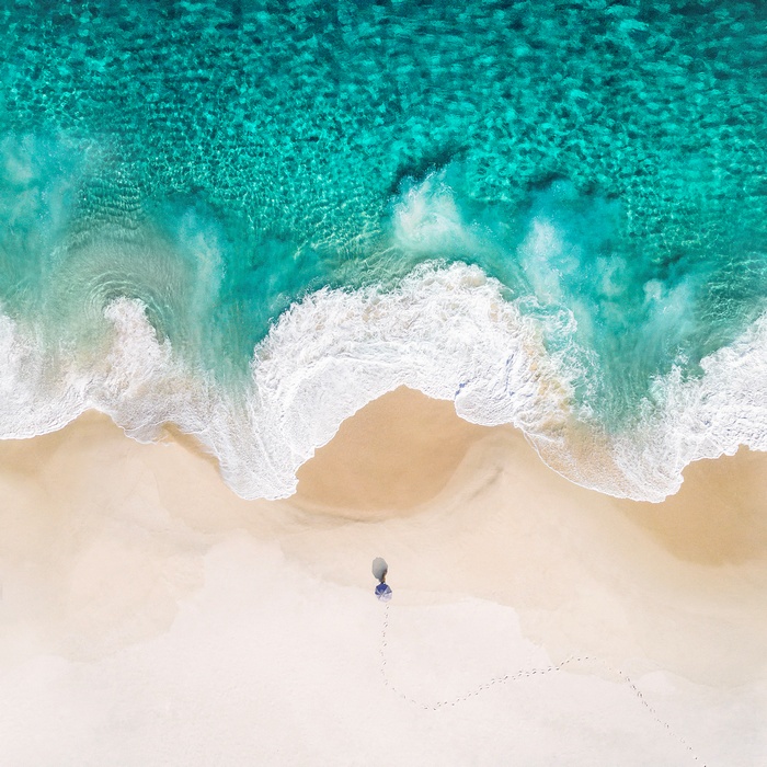 Person walking on a sandy beach with ocean waves