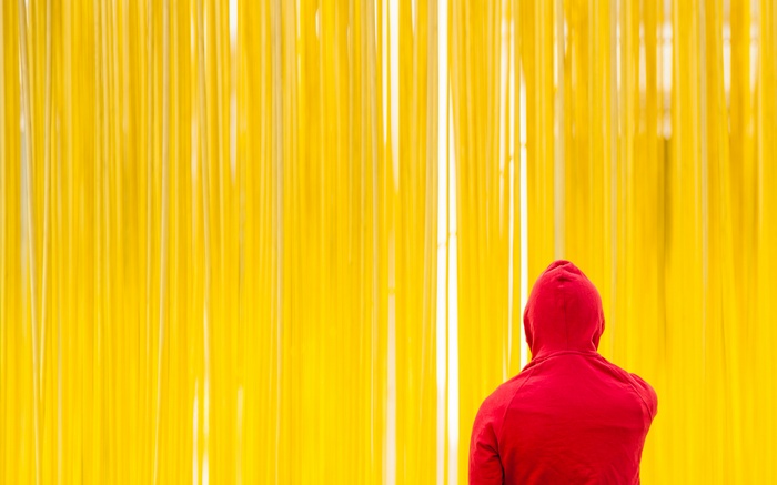 Person in red hoodie against yellow background