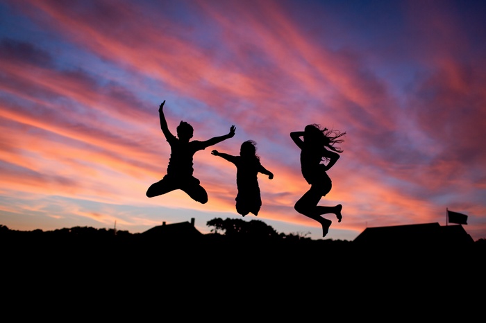 Three Silhouettes Jumping Against a Sunset Sky