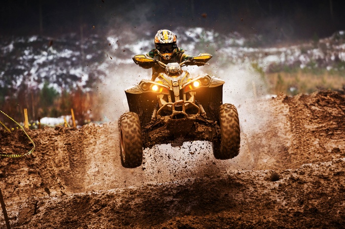 ATV Motocross Rider Jumps Over Muddy Terrain
