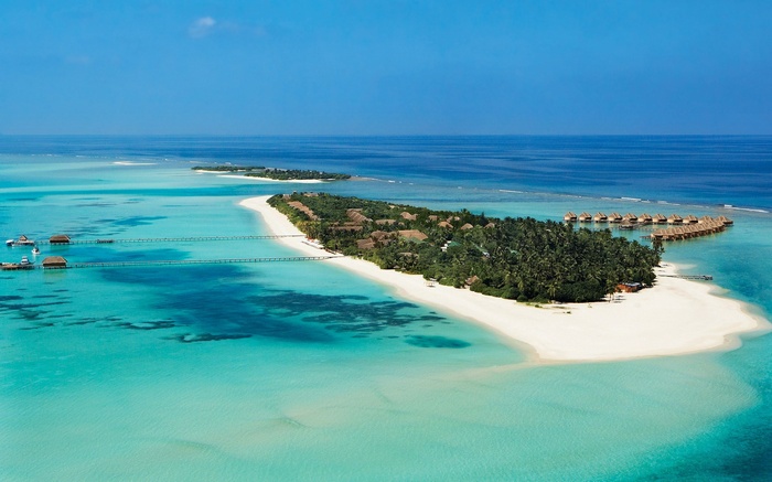 Aerial view of a tropical island resort with overwater bungalows
