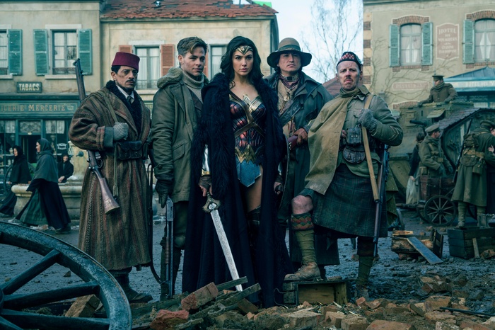 Wonder Woman and her companions in a war-torn town