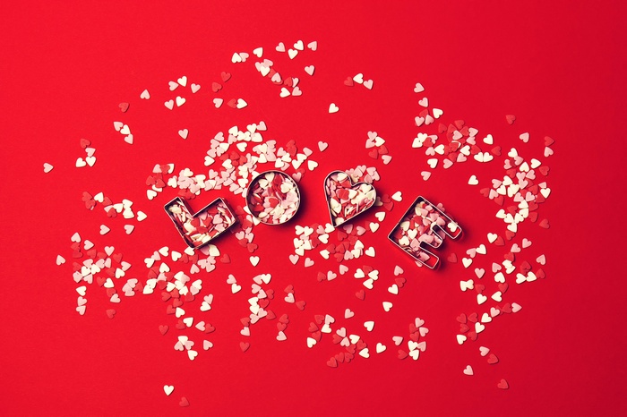 LOVE cookie cutters with heart sprinkles on red background