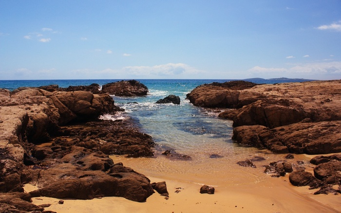 Rocky coastline with clear blue water and sandy beach