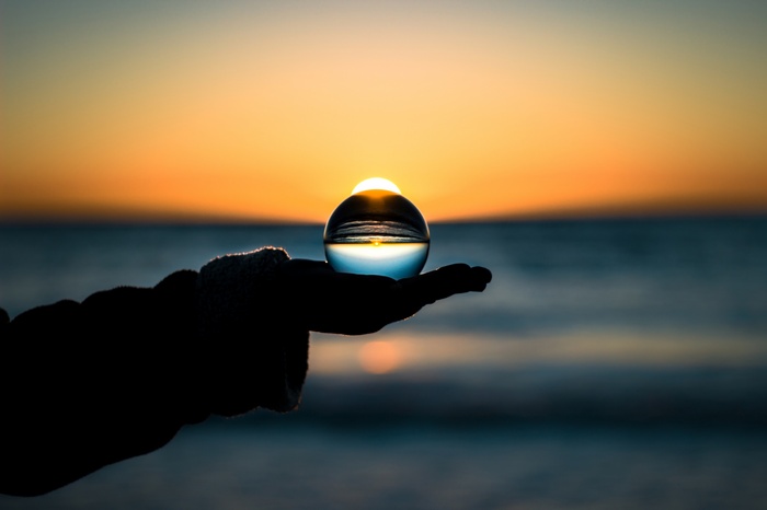 Sunset reflected in a crystal ball held in a hand