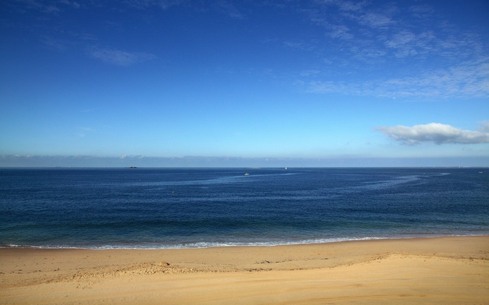 Sandy beach and blue ocean under a cloudy sky