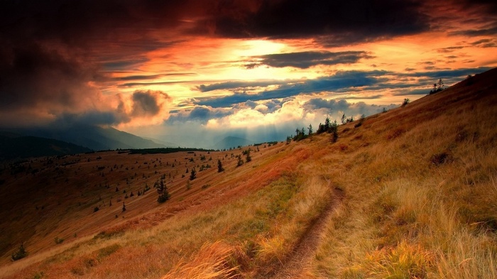 Mountain slope with a path at sunset