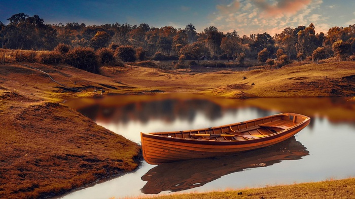 Wooden boat on a calm lake with trees in background