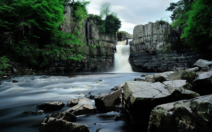 Waterfall cascading over rocky cliffs into a river