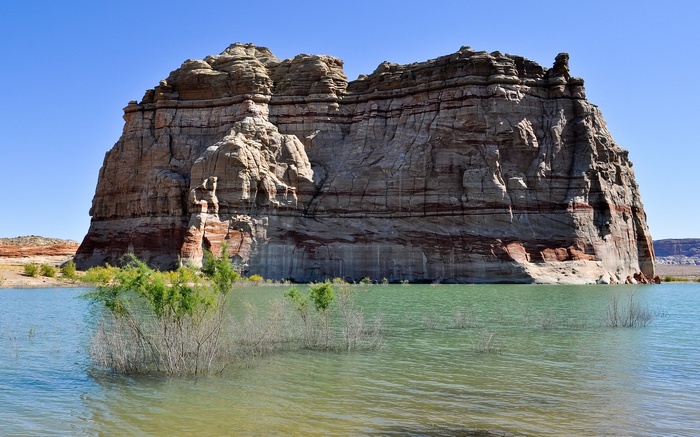 Layered sandstone cliffs rise from a lake