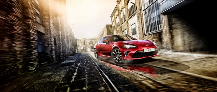 Red Toyota GT86 driving on train tracks