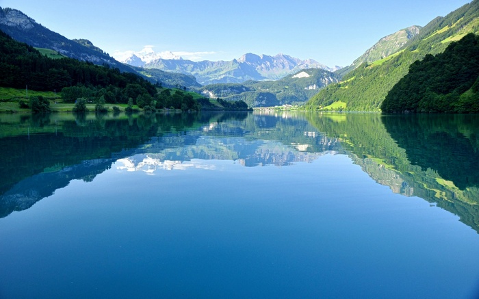Lake reflection of mountains and green hills