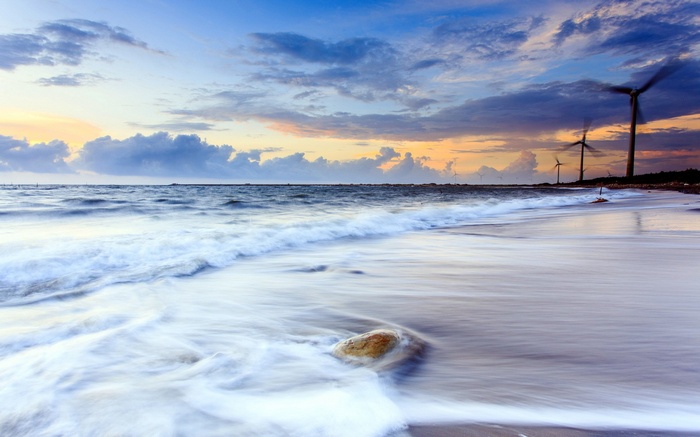 Wind turbines on a beach at sunset