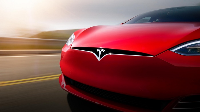 Red Tesla Model S driving on a road