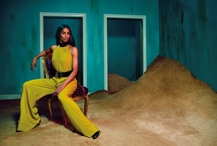 Ciara in a yellow jumpsuit sitting on a chair