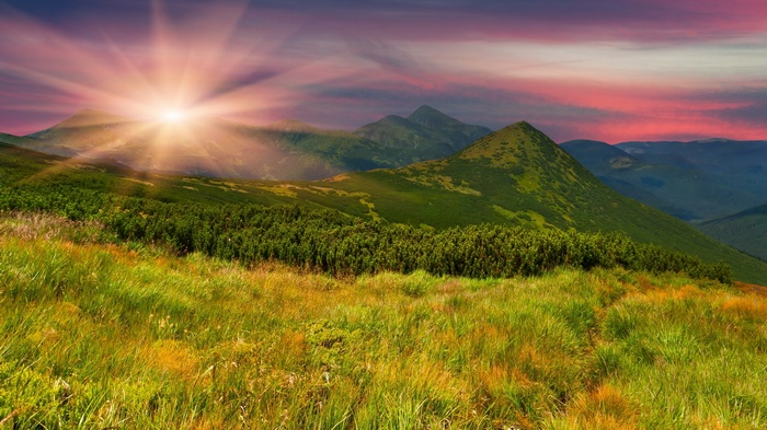 Sunrise over green mountains with colorful sky