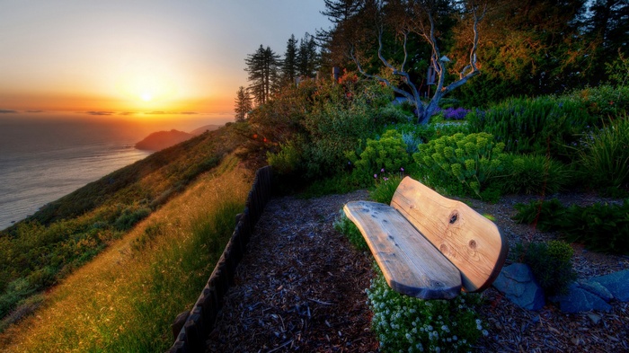 Wooden bench overlooking ocean at sunset