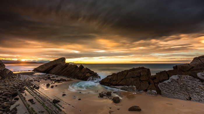 Rocky beach with crashing waves at sunset