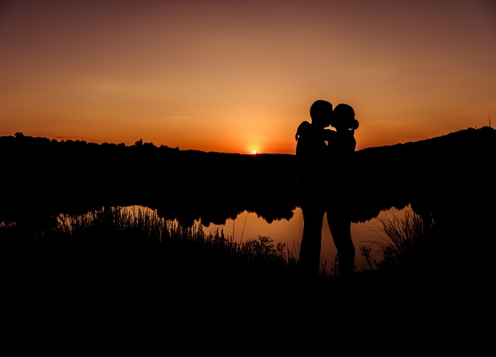 Couple kissing at sunset over a lake