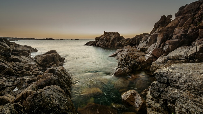 Rocky coastline with calm ocean at dusk
