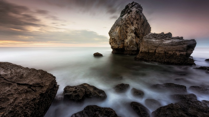 Rocky coastline with calm ocean at sunset