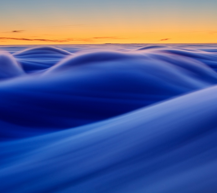 Abstract blue waves against an orange sky