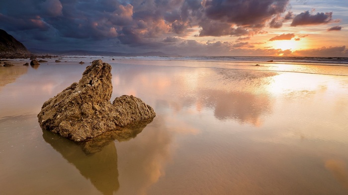 Rock on a beach at sunset