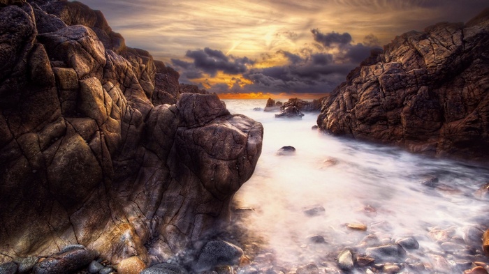 Rocky coastline with ocean waves at sunset