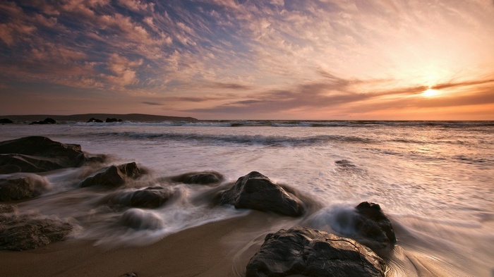 Sunset over a rocky beach with waves