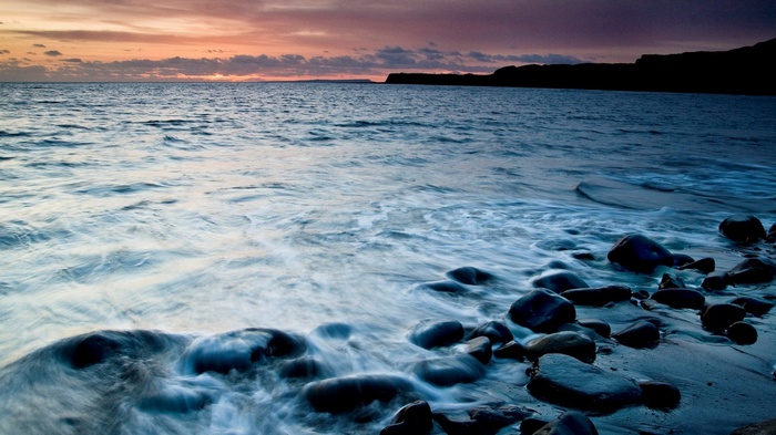 Ocean waves crashing on a rocky shore at sunset
