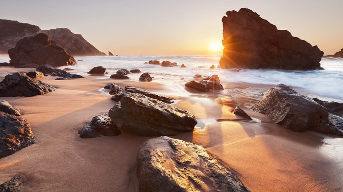 Sunset over a rocky beach with waves