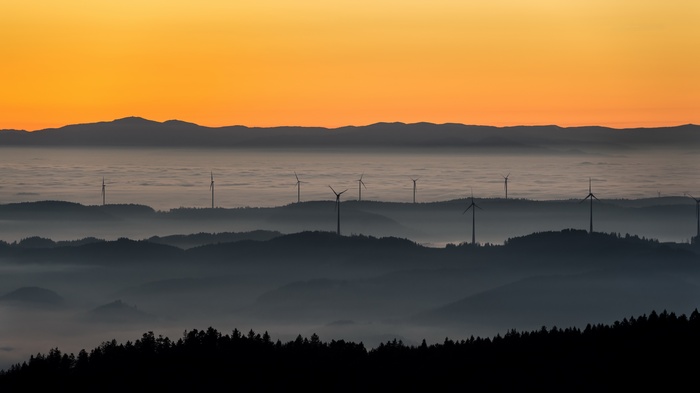 Wind turbines on misty hills at sunset