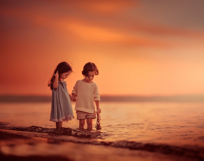 Two young girls holding hands at sunset