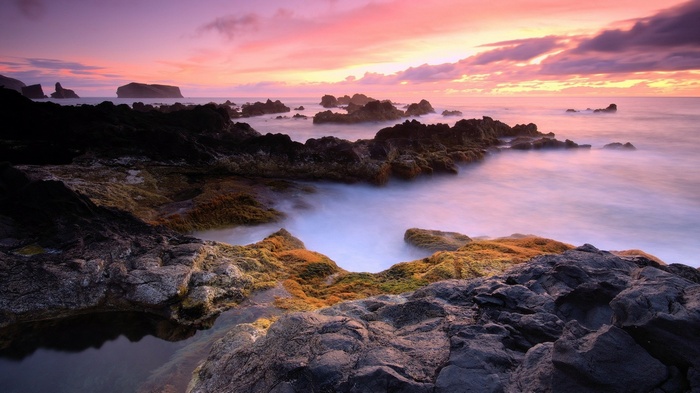 Rocky coastline at sunset with purple and pink sky