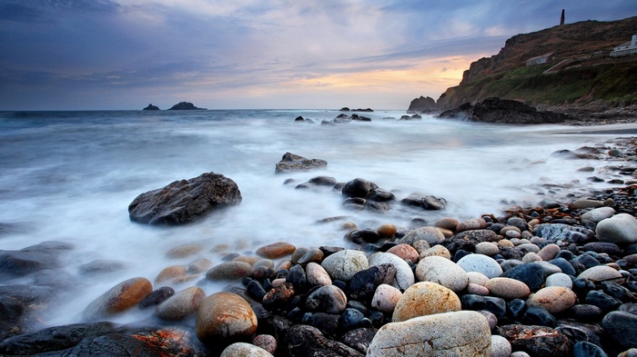 Rocky beach with waves and cliffs at sunset