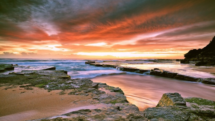 Ocean waves crashing on rocky shore at sunset