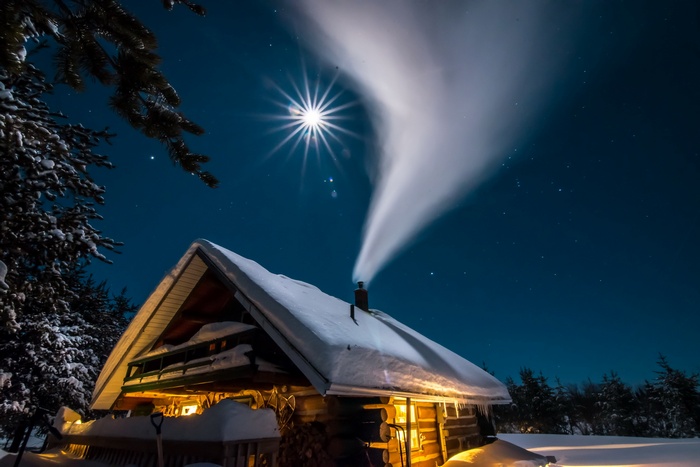 Log cabin with smoke rising under the moon at night
