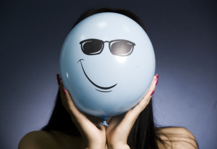 Person holding a smiley face balloon