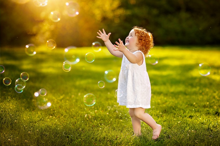 Young girl playing with bubbles in a meadow