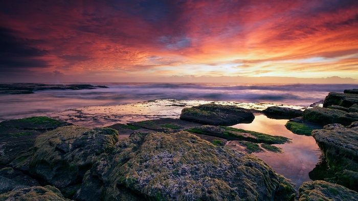Dramatic sunset over rocky coastline with ocean waves