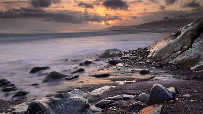 Rocky beach at sunset with ocean waves