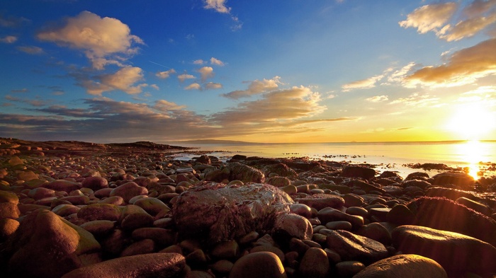 Rocky beach at sunset with ocean and clouds
