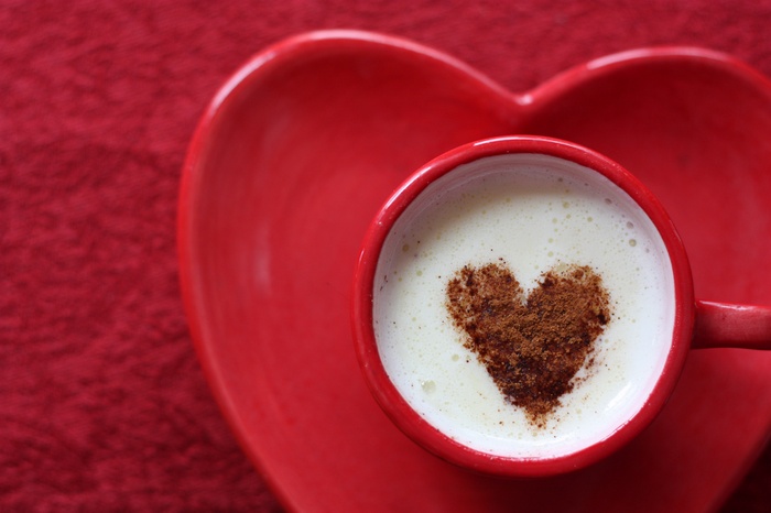 Coffee cup with heart shape on red saucer