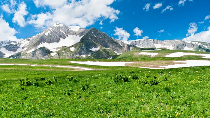 Snow mountains and green landscape with blue sky