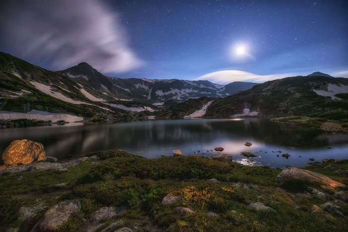Lake and mountains under the moonlit night sky