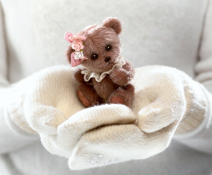 Cute teddy bear with pink bow in white mittens
