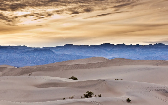 Sand dunes and mountains under a cloudy sky